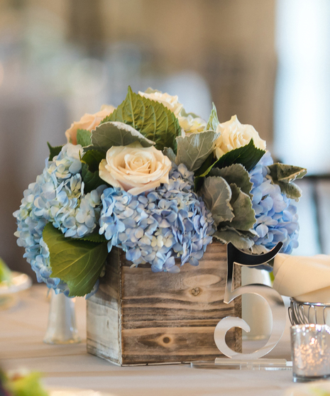 Blue and White Garden Table Centerpiece featuring blue hydrangea, white roses and dusty miller