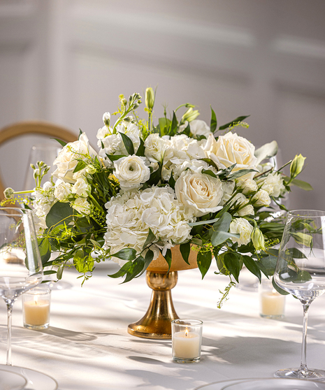 Table Centerpiece in pedestal container featuring white seasonal flowers